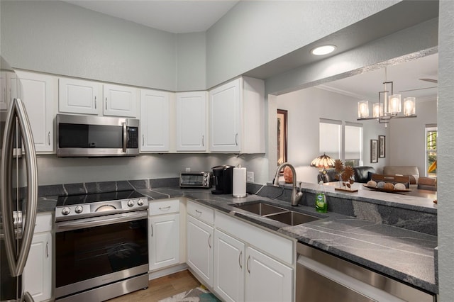 kitchen featuring white cabinets, sink, stainless steel appliances, and a chandelier