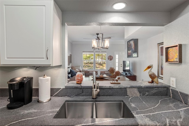 kitchen featuring ornamental molding, sink, decorative light fixtures, a chandelier, and white cabinetry