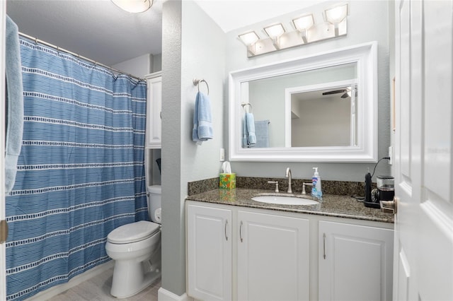 bathroom featuring walk in shower, vanity, toilet, and ceiling fan