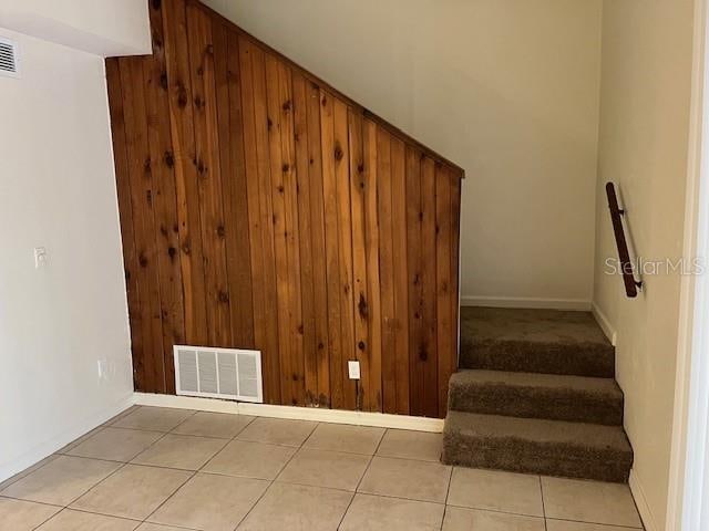 stairs featuring tile patterned floors and wood walls