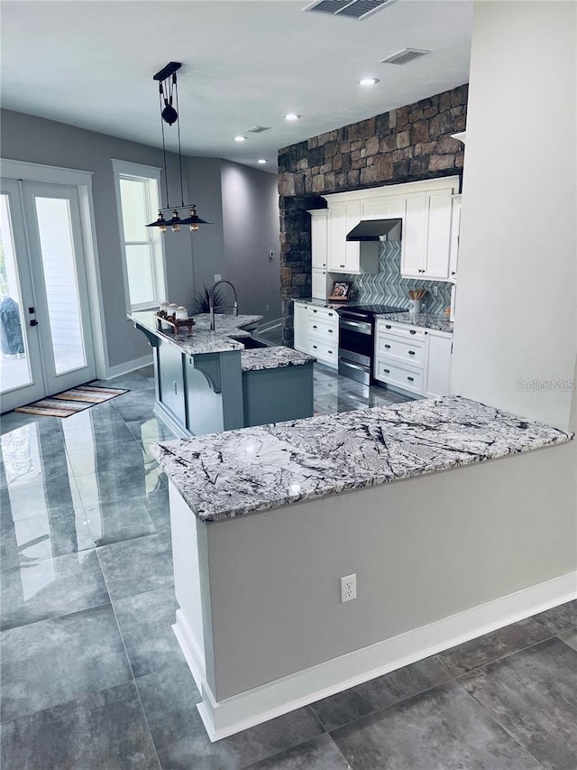 kitchen with pendant lighting, a breakfast bar, a kitchen island with sink, white cabinets, and stainless steel electric stove