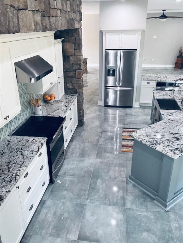 kitchen featuring stainless steel appliances, light stone countertops, extractor fan, and white cabinets