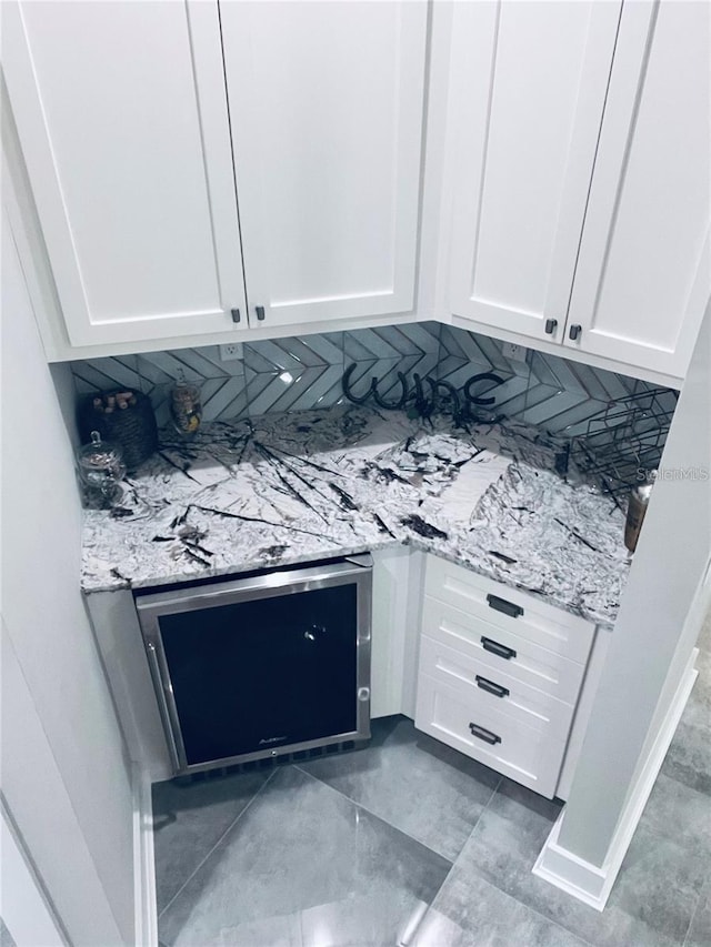 kitchen featuring backsplash, light stone countertops, and white cabinets