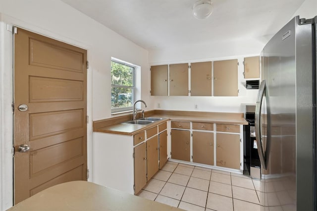 kitchen featuring stainless steel fridge, light tile patterned floors, and sink