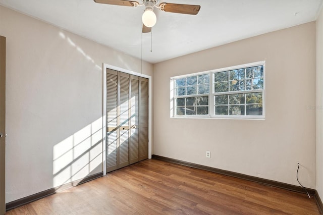 unfurnished bedroom featuring hardwood / wood-style flooring, ceiling fan, and a closet