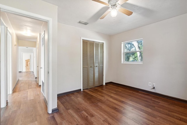 unfurnished bedroom with ceiling fan, wood-type flooring, and a closet