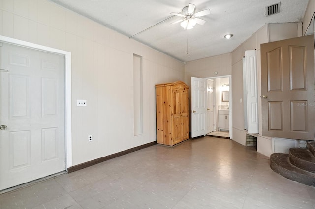 unfurnished bedroom featuring a textured ceiling, ensuite bath, and ceiling fan