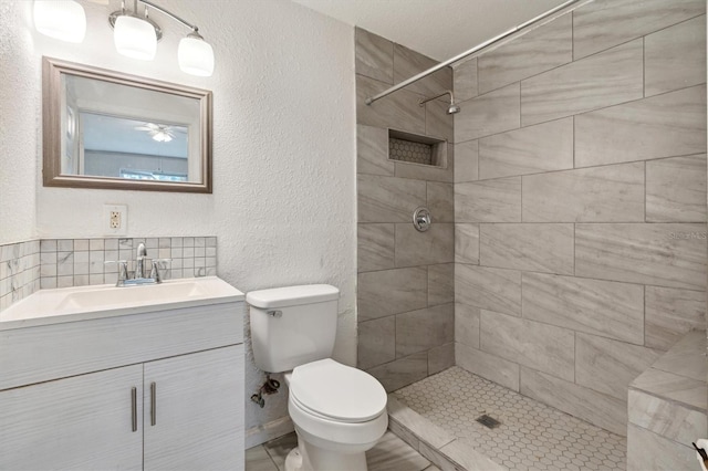 bathroom with tiled shower, vanity, and toilet