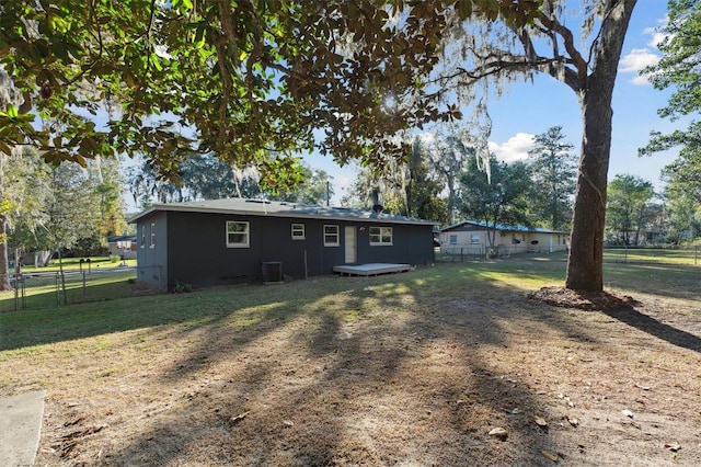 rear view of property featuring central AC unit, a deck, and a yard