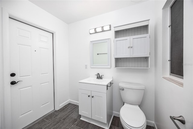 bathroom with baseboards, vanity, and toilet