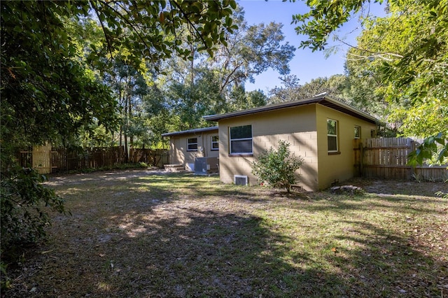 back of property with a yard, concrete block siding, and fence