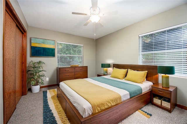 bedroom featuring baseboards, ceiling fan, a closet, and light colored carpet