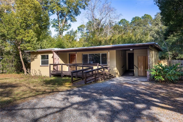 view of front of house featuring a carport, concrete block siding, driveway, and a wooden deck