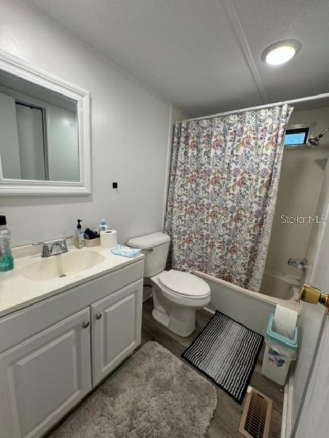 full bathroom with hardwood / wood-style flooring, vanity, toilet, and shower / bath combo with shower curtain