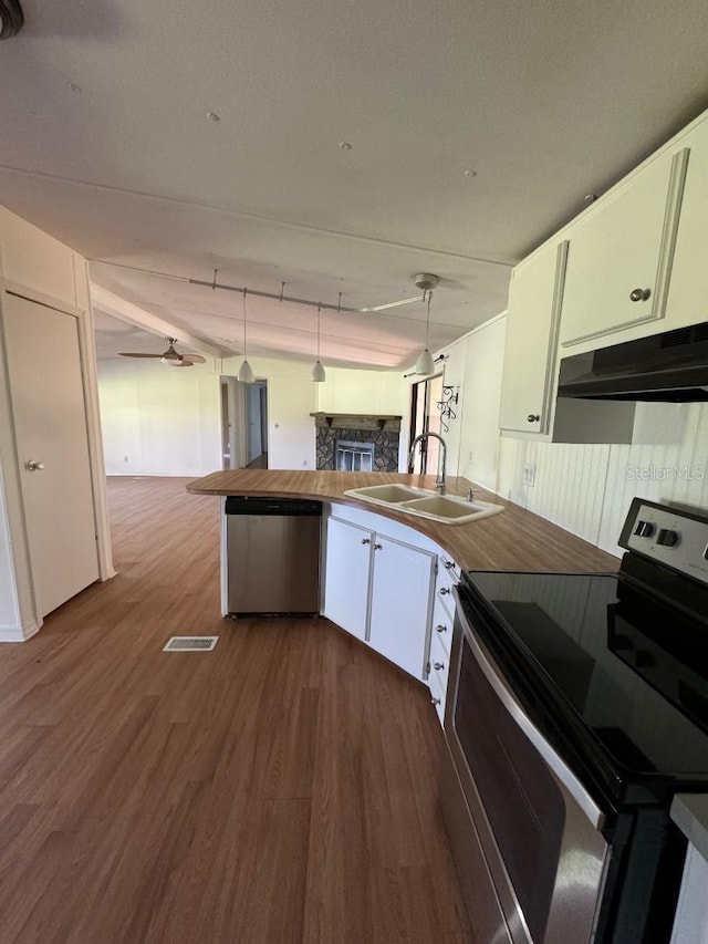 kitchen featuring appliances with stainless steel finishes, sink, hardwood / wood-style flooring, white cabinetry, and hanging light fixtures