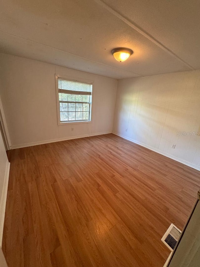 empty room featuring wood-type flooring and a textured ceiling