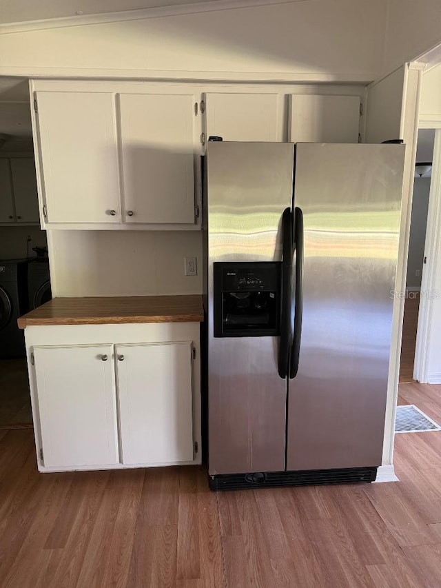 kitchen featuring hardwood / wood-style floors, washer and clothes dryer, stainless steel refrigerator with ice dispenser, vaulted ceiling, and white cabinetry