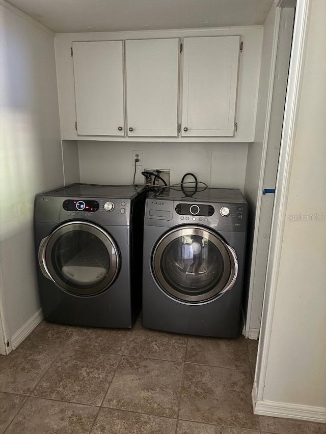 laundry area featuring washing machine and clothes dryer and cabinets