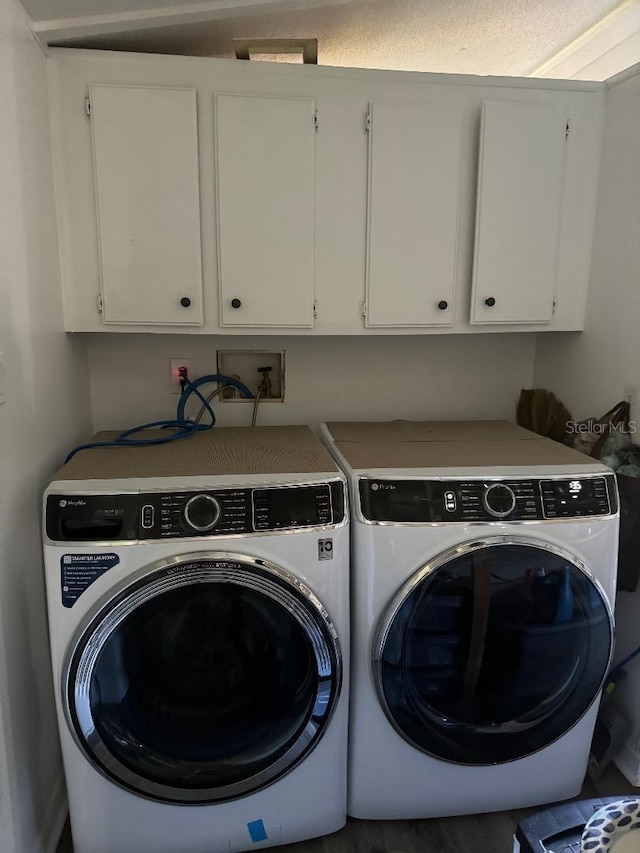 clothes washing area featuring washer and dryer and cabinets