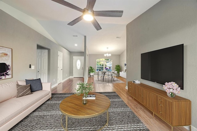 living room featuring ceiling fan with notable chandelier, lofted ceiling, and light hardwood / wood-style flooring