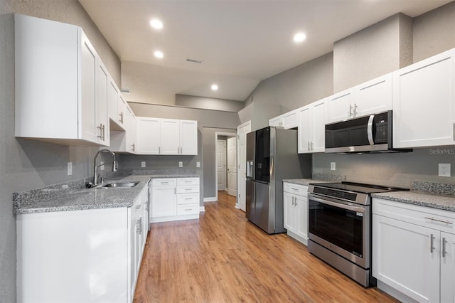 kitchen with white cabinetry, sink, stainless steel appliances, and light hardwood / wood-style flooring