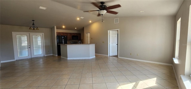 interior space with french doors, ceiling fan with notable chandelier, lofted ceiling, and light tile patterned floors