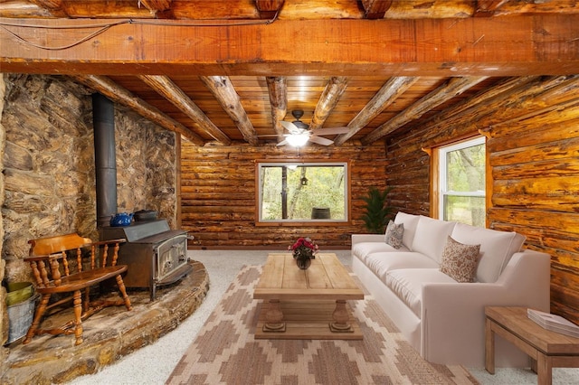 carpeted living room featuring beamed ceiling, plenty of natural light, a wood stove, and wood ceiling