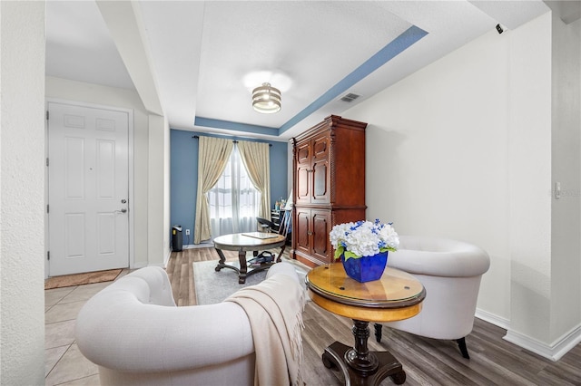 living area with light wood-type flooring and a tray ceiling