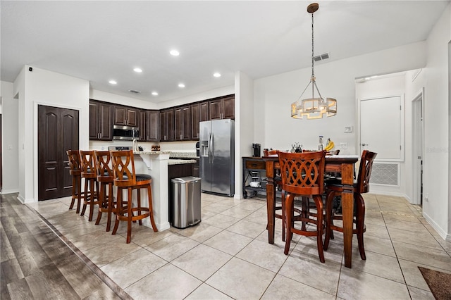 kitchen featuring pendant lighting, a center island, an inviting chandelier, dark brown cabinetry, and stainless steel appliances