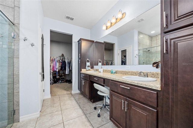 bathroom with a shower with door, vanity, and tile patterned flooring