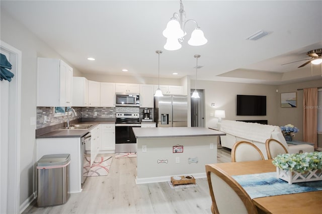 kitchen featuring pendant lighting, sink, light hardwood / wood-style flooring, appliances with stainless steel finishes, and white cabinetry