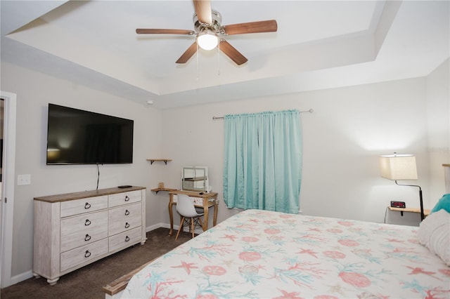 carpeted bedroom with ceiling fan and a tray ceiling