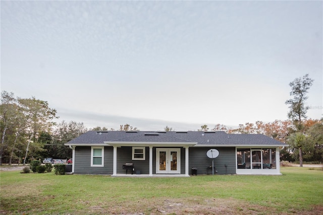 back of property with french doors, a yard, and a sunroom