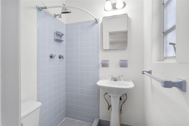 bathroom featuring a tile shower and toilet