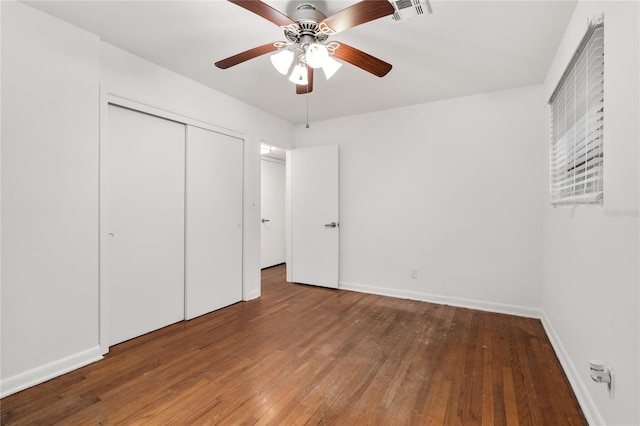 unfurnished bedroom with ceiling fan, a closet, and dark hardwood / wood-style floors