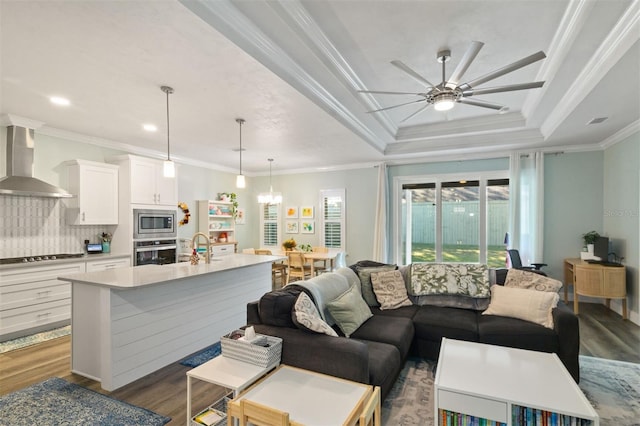 living room featuring a raised ceiling, ceiling fan, crown molding, sink, and dark hardwood / wood-style floors