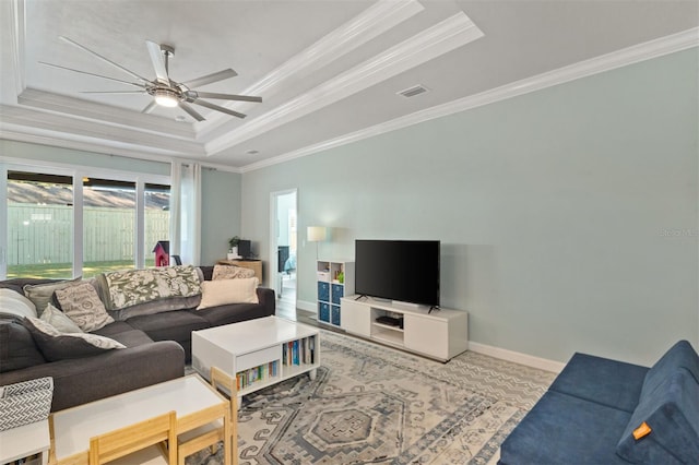 living room with a raised ceiling, ceiling fan, and ornamental molding