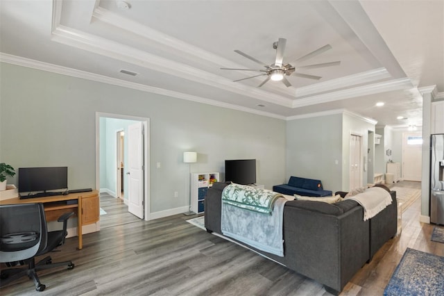 living room with hardwood / wood-style flooring, ceiling fan, a raised ceiling, and crown molding