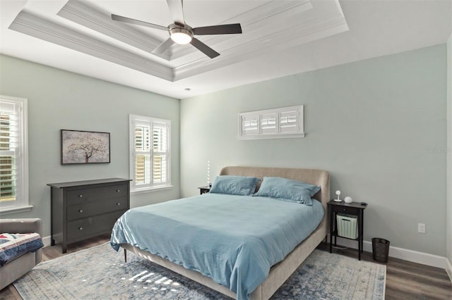 bedroom featuring a raised ceiling, ceiling fan, dark hardwood / wood-style flooring, and ornamental molding