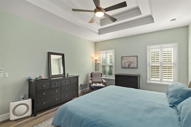 bedroom with ceiling fan, a raised ceiling, light hardwood / wood-style flooring, and multiple windows