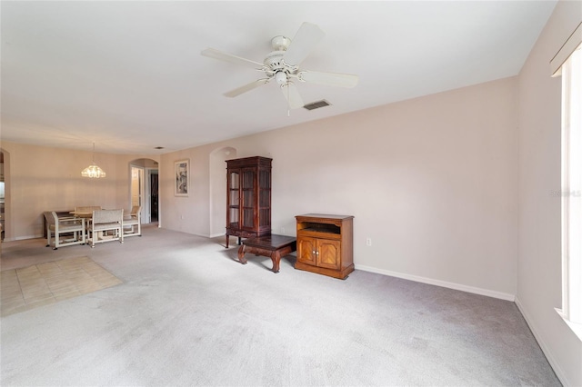 unfurnished living room with carpet flooring and ceiling fan with notable chandelier