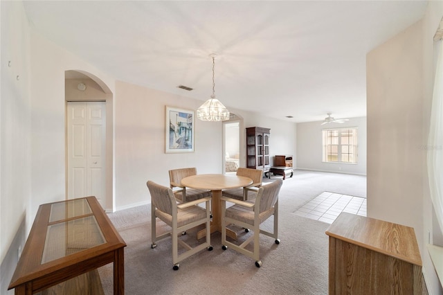 carpeted dining room with ceiling fan with notable chandelier