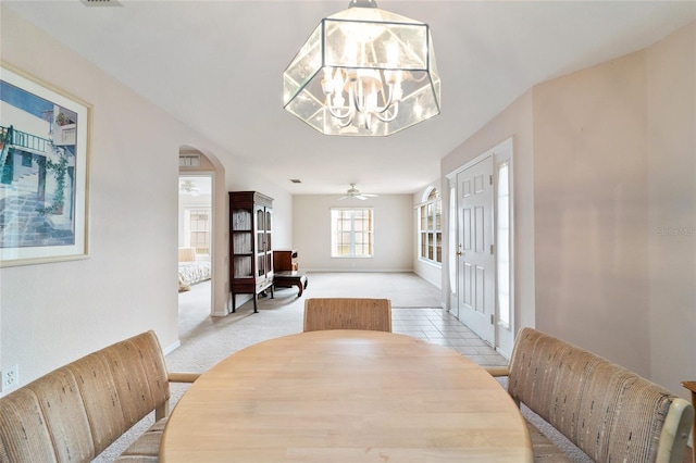 carpeted dining space with ceiling fan with notable chandelier