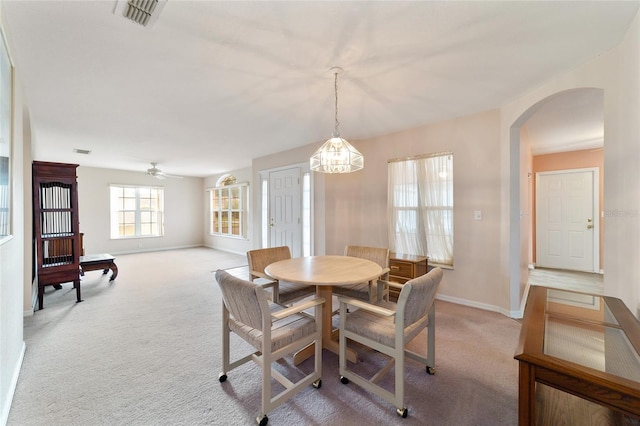 dining area featuring ceiling fan with notable chandelier and light colored carpet