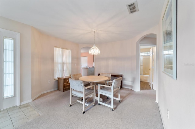 dining area featuring light colored carpet, a wealth of natural light, and a notable chandelier