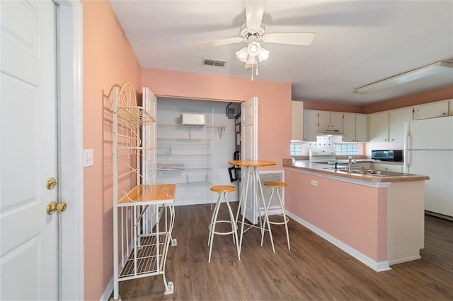 kitchen with sink, dark hardwood / wood-style flooring, white appliances, and kitchen peninsula