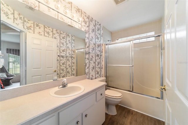 full bathroom featuring hardwood / wood-style flooring, vanity, toilet, and enclosed tub / shower combo