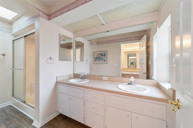 bathroom featuring a skylight, vanity, an enclosed shower, and hardwood / wood-style flooring