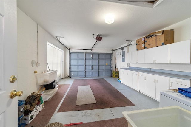 garage featuring electric panel, washer / dryer, and a garage door opener