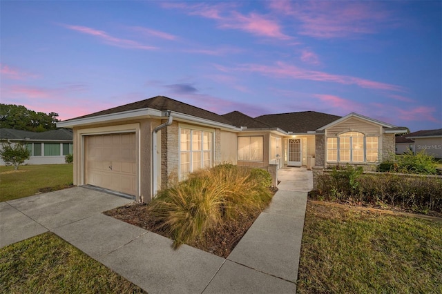 ranch-style house featuring a garage and a lawn